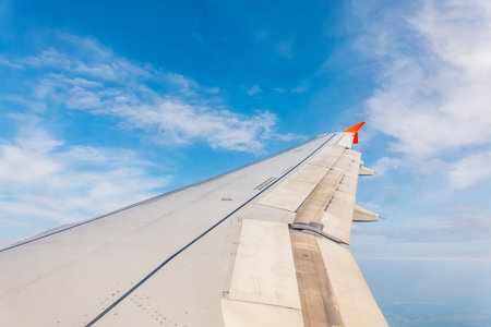 View from the airplane window at a beautiful cloudy sky and the airplane wing. Earth and sky as seen through window of an airplane.の写真素材