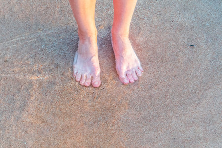 Beach - women's foot and the grains of sand. Feet of a woman on a sand
