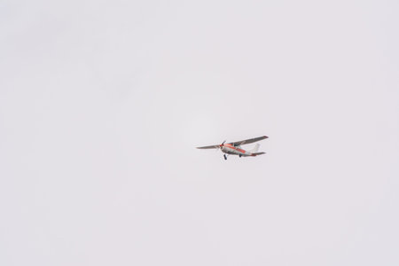 Small ultralight airplane with overhead wing and single propeller flying in sunset sky. Such...