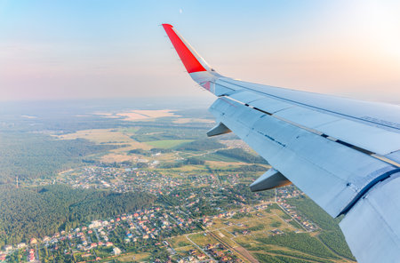 View of airplane wing, blue skies and green land during landing. Airplane window view. Earth and sky as seen through window of an airplane.の写真素材