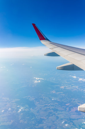 View from the airplane window at a beautiful cloudy sky and the airplane wing. Earth and sky as seen through window of an airplane.の写真素材