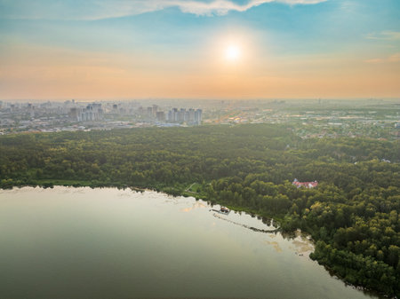 Big lake with green shores in bright sun light and city on horizon, aerial landscape. Recreation concept. Sky reflection. Ecology in Europe. Aerial view. Lake Shartash and Yekaterinburg, Russiaの写真素材