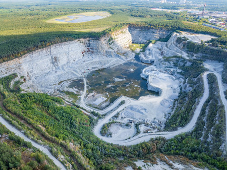 Stone quarry in the forest. Flying over the summer mixed forest during sunset. Stone crushing plant....