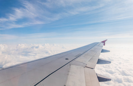 View from the airplane window at a beautiful cloudy sky and the airplane wing. Earth and sky as seen through window of an airplane.の写真素材