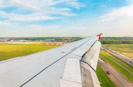 View of airplane wing, blue skies and green land during landing. Airplane window view. Earth and sky as seen through window of an airplane.の写真素材