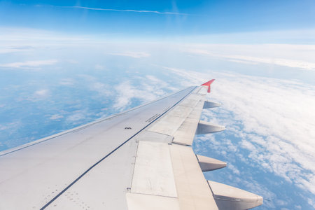 View from the airplane window at a beautiful cloudy sky and the airplane wing. Earth and sky as seen through window of an airplane.の写真素材