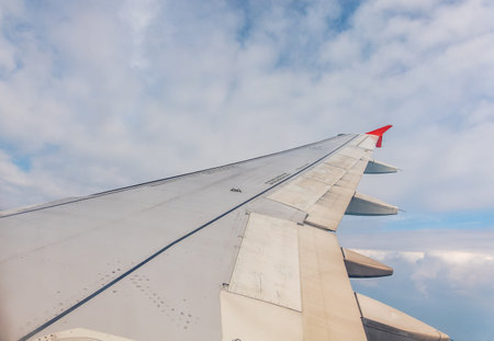 View from the airplane window at a beautiful cloudy sky and the airplane wing. Earth and sky as seen...