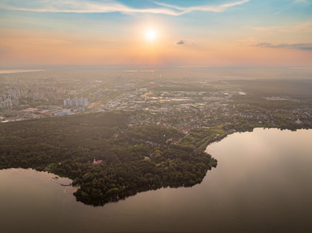 Big lake with green shores in bright sun light and city on horizon, aerial landscape. Recreation concept. Sky reflection. Ecology. Aerial view.の写真素材