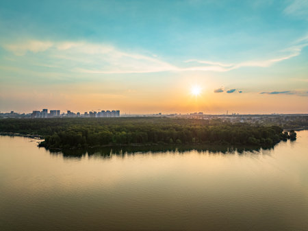 Big lake with green shores in bright sun light and city on horizon, aerial landscape. Recreation concept. Sky reflection. Ecology. Aerial view.の写真素材