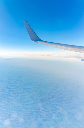 View from the airplane window at a beautiful cloudy sky and the airplane wing. Earth and sky as seen through window of an airplane.の写真素材