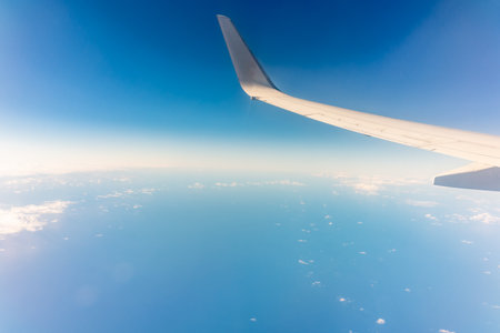 View from the airplane window at a beautiful clear blue sky and the airplane wing. Earth and sky as seen through window of an airplane.の写真素材