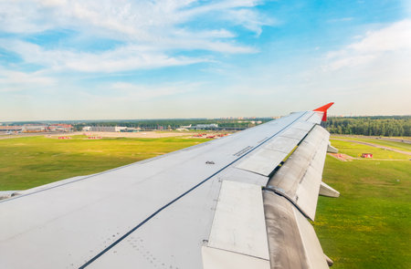 View of airplane wing, blue skies and green land during landing. Airplane window view. Earth and sky as seen through window of an airplane.の写真素材
