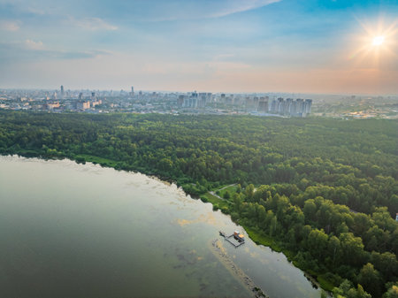 Big lake with green shores in bright sun light and city on horizon, aerial landscape. Recreation concept. Sky reflection. Ecology. Aerial view.の写真素材
