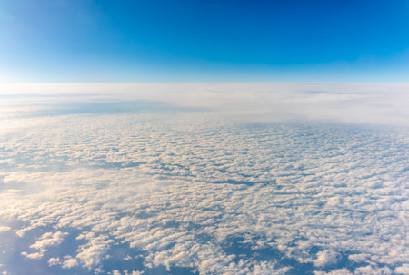 View from the airplane window at a beautiful cloudy sky and the airplane wing. Earth and sky as seen through window of an airplane.の写真素材