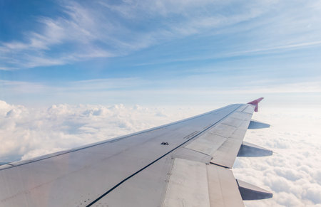 View from the airplane window at a beautiful cloudy sky and the airplane wing. Earth and sky as seen through window of an airplane.の写真素材