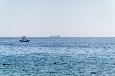 Calm blue sea with the silhouette of a large ship on the horizon. Blue sea with Cargo ship on the backgroundの写真素材