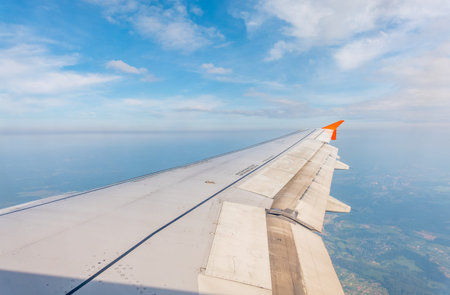 View from the airplane window at a beautiful cloudy sky and the airplane wing. Earth and sky as seen...