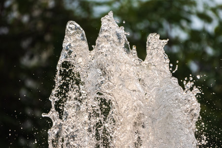 Water splashes from fountain on dark background. Natural texture of only water of fountain. High waves effect in hot summer with copy space. Water sprays in sunny day close-up.の写真素材