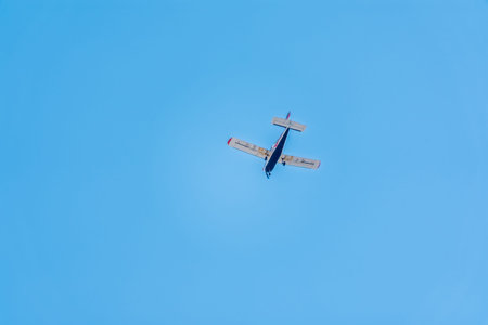 Small ultralight airplane with overhead wing and single propeller flying in sky. Such aircraft are...