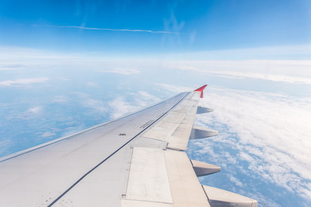 View from the airplane window at a beautiful cloudy sky and the airplane wing. Earth and sky as seen through window of an airplane.の写真素材