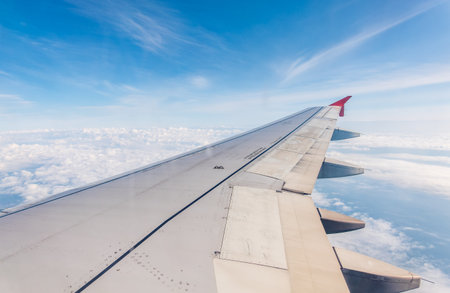 View from the airplane window at a beautiful cloudy sky and the airplane wing. Earth and sky as seen through window of an airplane.の写真素材