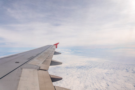 View from the airplane window at a beautiful cloudy sky and the airplane wing. Earth and sky as seen...