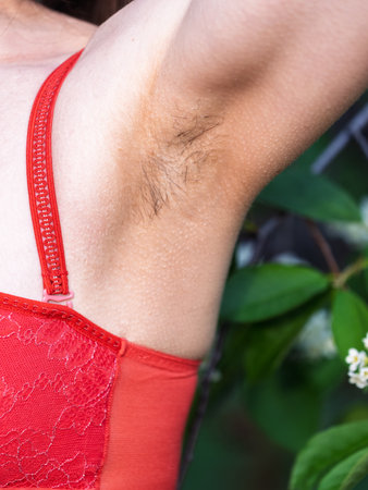 Closeup of long dark hair growing under arm of young female. Concept of hygiene, Female hairy armpit, unshaved underarms new fashion trend concept. Feminism, Beauty standards, skin, body care conceptの写真素材
