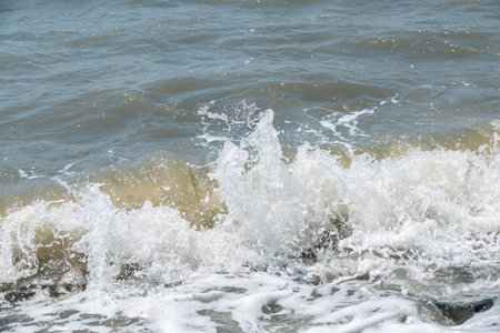 Sea water splashing over the stones on the beach. Splashes and drops of water on a blue sea...