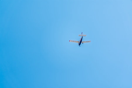 Small ultralight airplane with overhead wing and single propeller flying in sunset sky. Such...