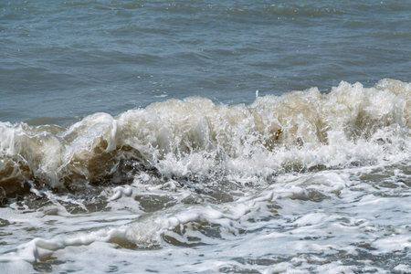 Sea water splashing over the stones on the beach. Splashes and drops of water on a blue sea...
