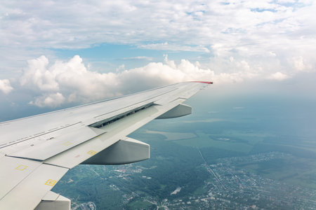 View of airplane wing, blue skies and green land during landing. Airplane window view. Earth and sky...