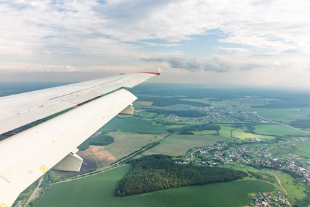 View of airplane wing, blue skies and green land during landing. Airplane window view. Earth and sky...
