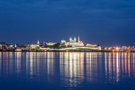 Night view of the Kazan Kremlin. Illuminated buildings and lanterns on the river bank, the multicolored lights of the night city reflected in the waterの写真素材