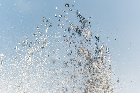Splashes of water against light background. A jet of water against cloudy sky.