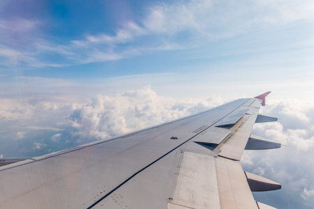 View from the airplane window at a beautiful cloudy sky and the airplane wing. Earth and sky as seen through window of an airplane.の写真素材