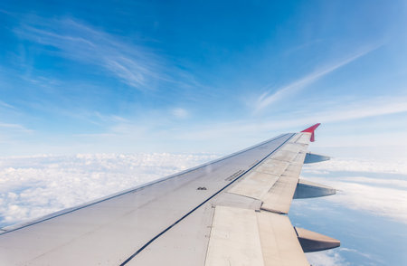 View from the airplane window at a beautiful cloudy sky and the airplane wing. Earth and sky as seen through window of an airplane.の写真素材