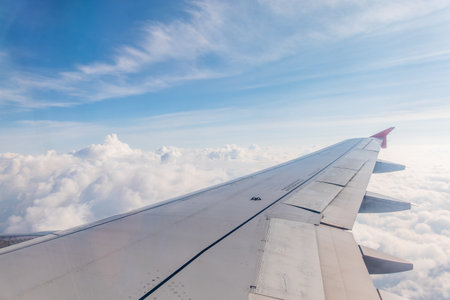 View from the airplane window at a beautiful cloudy sky and the airplane wing. Earth and sky as seen through window of an airplane.の写真素材