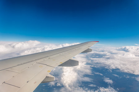 View from the airplane window at a beautiful cloudy sky and the airplane wing. Earth and sky as seen through window of an airplane.の写真素材