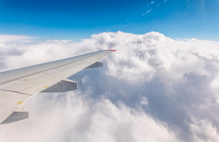 View from the airplane window at a beautiful cloudy sky and the airplane wing. Earth and sky as seen through window of an airplane.の写真素材