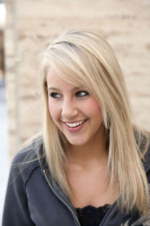 Attractive young woman in a gray hoodie smiles outside. Vertical shot.の写真素材