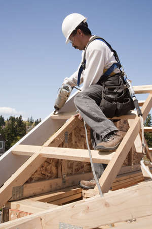 Construction worker fastening wooden beams on top of a partially built structure. Vertical shot.の写真素材