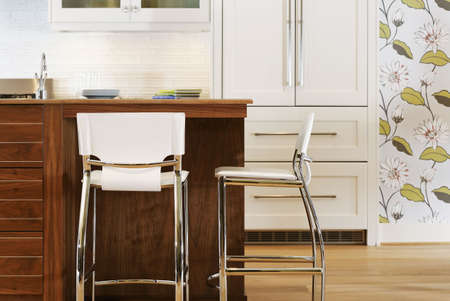 Quaintly decorated kitchen with chairs set at an island in the middle. There is flowered wallpaper on the wall. Horizontal shot.の写真素材