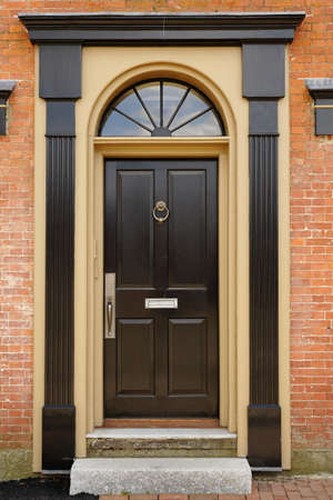 An elegant brown door with brass accents in a brick building. Vertical shot.の写真素材