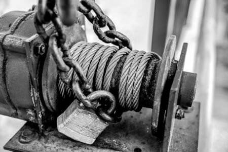 black and white of old industrial cable winch with padlockの写真素材