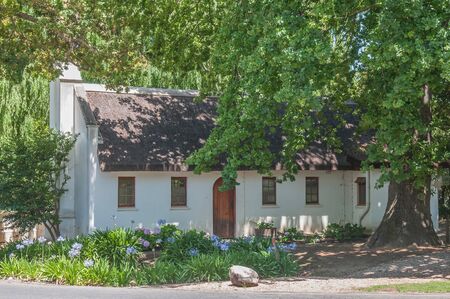 CAPE TOWN, SOUTH AFRICA - DECEMBER 15, 2014:  Historic old house under a very old and big oak tree on the farm Lourensford near Somerset Westのeditorial素材