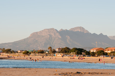 CAPE TOWN, SOUTH AFRICA - DECEMBER 17, 2014: Unidentified people at sunset on a beach in Gordens Bay with the HelderbergMountain in the backのeditorial素材