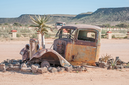 FISH RIVER CANYON, NAMIBIA - JUNE 17, 2011: A quiver tree growing through the bonnet of an old car at a lodge near the Fish River Canyonのeditorial素材