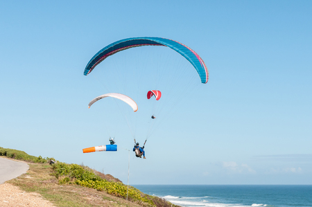PORT ELIZABETH, SOUTH AFRICA - FEBRUARY 27, 2016:  Three paragliders in the air next to a windsock at Beachview near Port Elizabethのeditorial素材