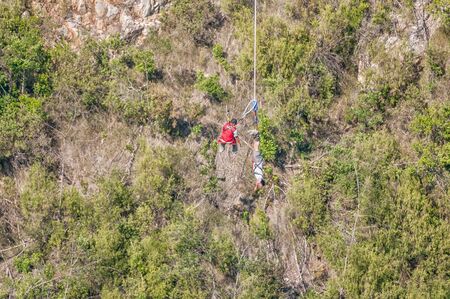 An official preparing to hoist an unidentified bungee jumper back to the bridge after the worlds highest commercial bungee jump at the Bloukrans Bridgeのeditorial素材