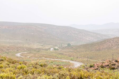 A wet Nuwekloofpas (new valley pass) descending into the Baviaanskloof (baboon valley) during a rain stormの写真素材